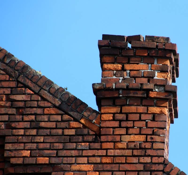 Damaged chimney on an Commerce home showing cracks and missing mortar